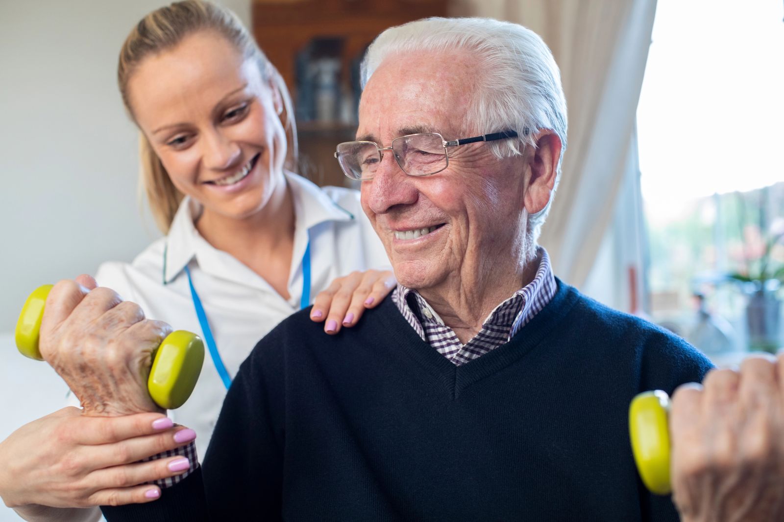 A smiling carer exercising with an older man