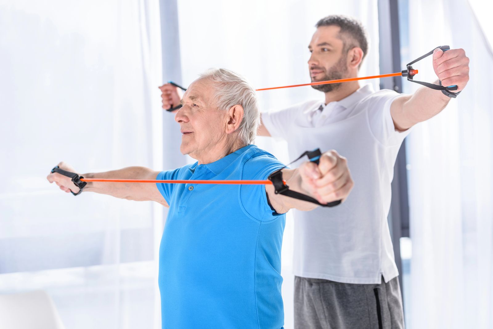 A physiotherapist and an older man exercising with resistance bands
